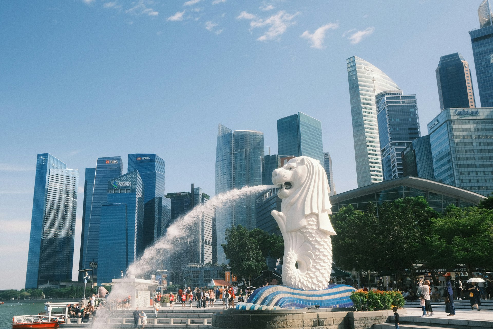 A statue of a dog spewing water in front of a city skyline